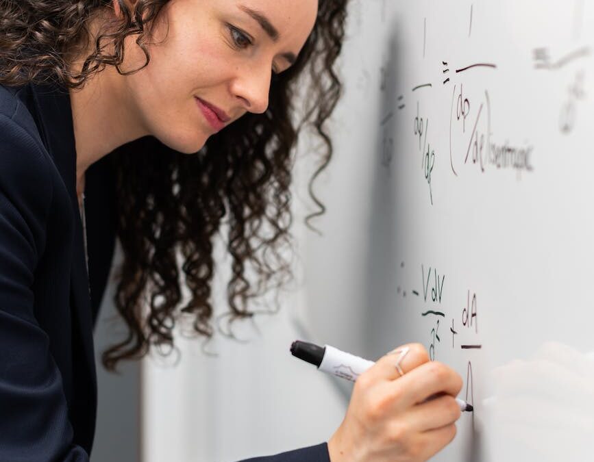 woman writing formula on whiteboard